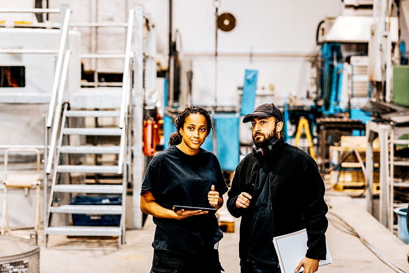 Two colleagues discussing work on a factory floor