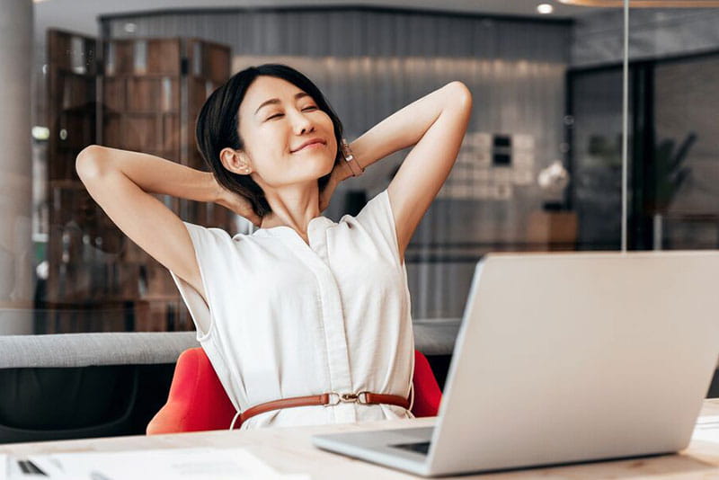 Woman relaxing at her desk after working on a laptop