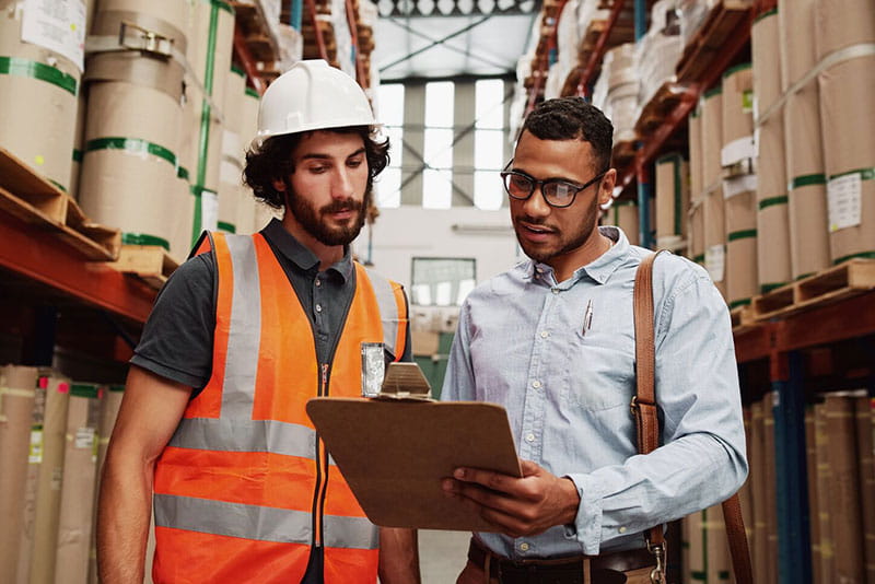 Warehouse worker and manager reviewing documents together