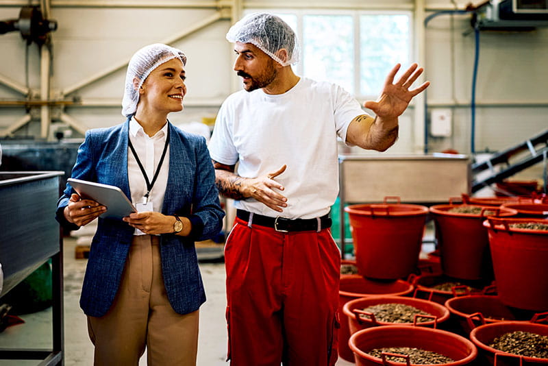 Manager and production worker discussing operations in a food processing facility
