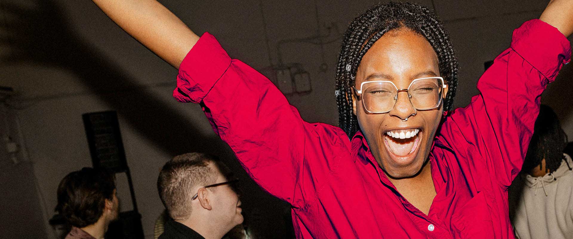 Person celebrating with raised arms in social setting