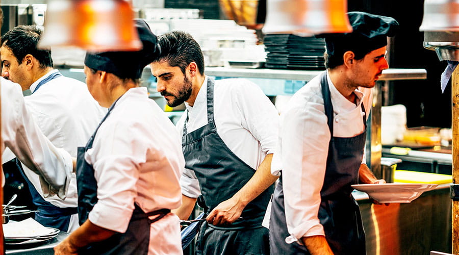 Chefs working together in busy commercial kitchen Chefs working together in busy commercial kitchen