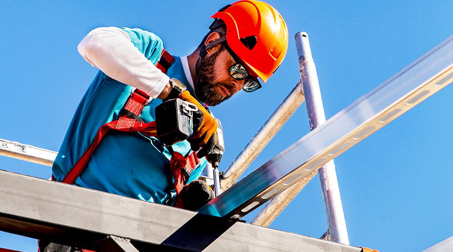 Arbeiter sichert Stahlträger in der Höhe mit Schutzausrüstung