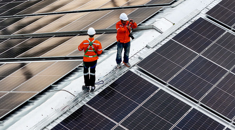 Workers installing solar panels on rooftop Workers installing solar panels on rooftop