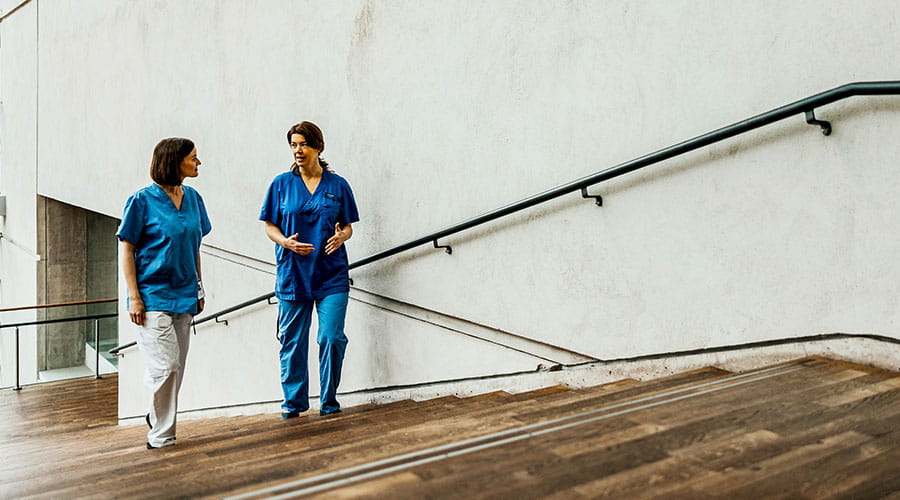 Deux travailleurs de la santé marchant à l'extérieur d'un bâtiment Deux travailleurs de la santé marchant à l'extérieur d'un bâtiment