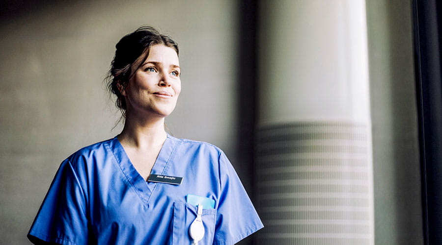 Enfermero en uniforme médico de pie cerca de una ventana Enfermero en uniforme médico de pie cerca de una ventana