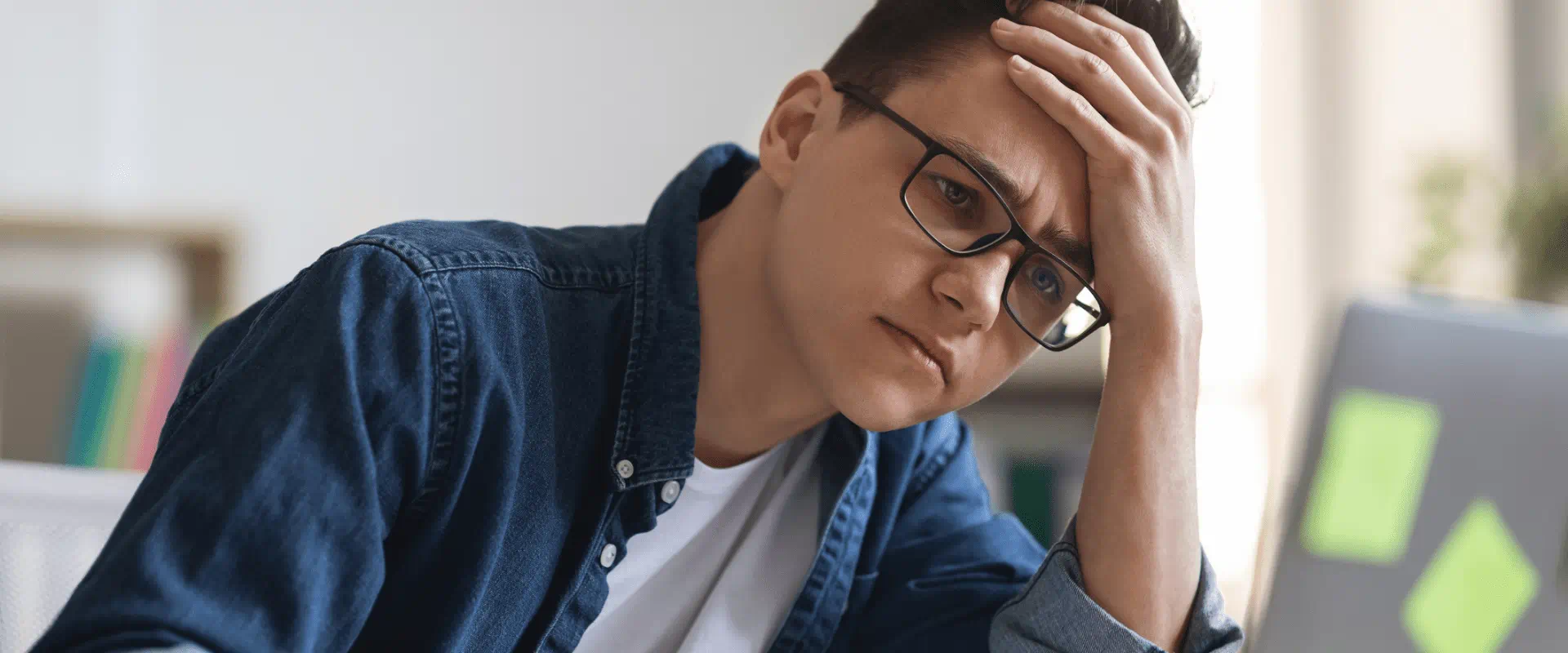 A young person sits at a desk, looking overwhelmed.