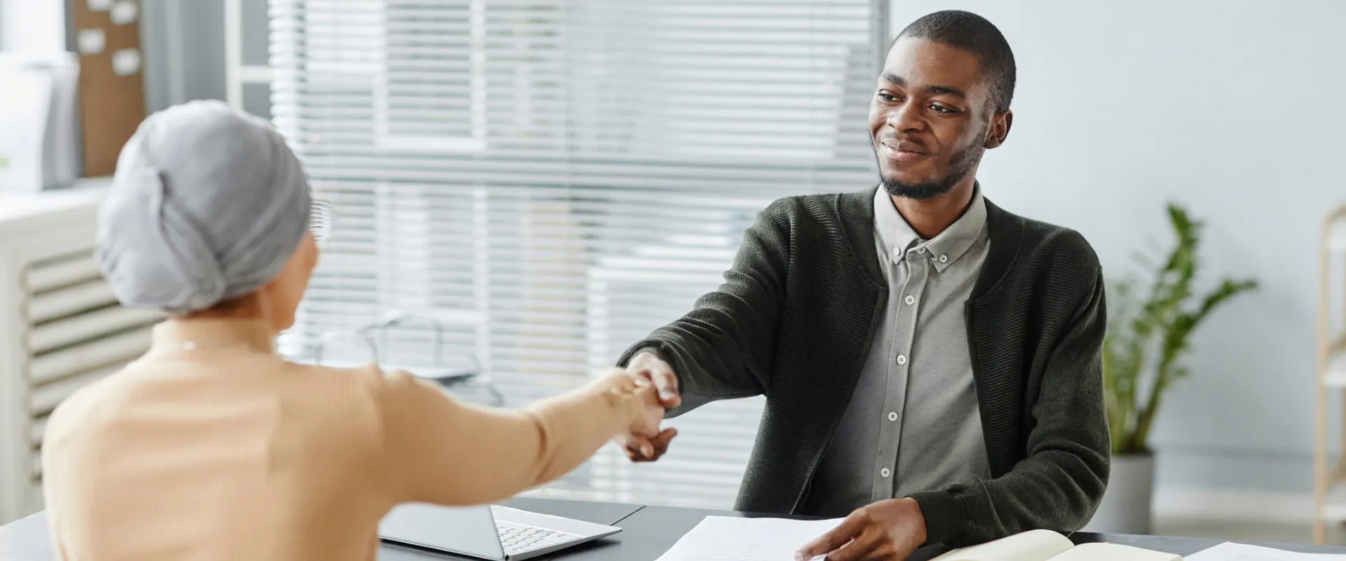 A professional extending a handshake during a business meeting in a modern office.