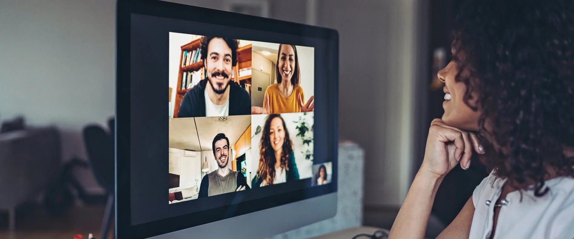A professional engaged in a video conference call with colleagues on a computer screen.