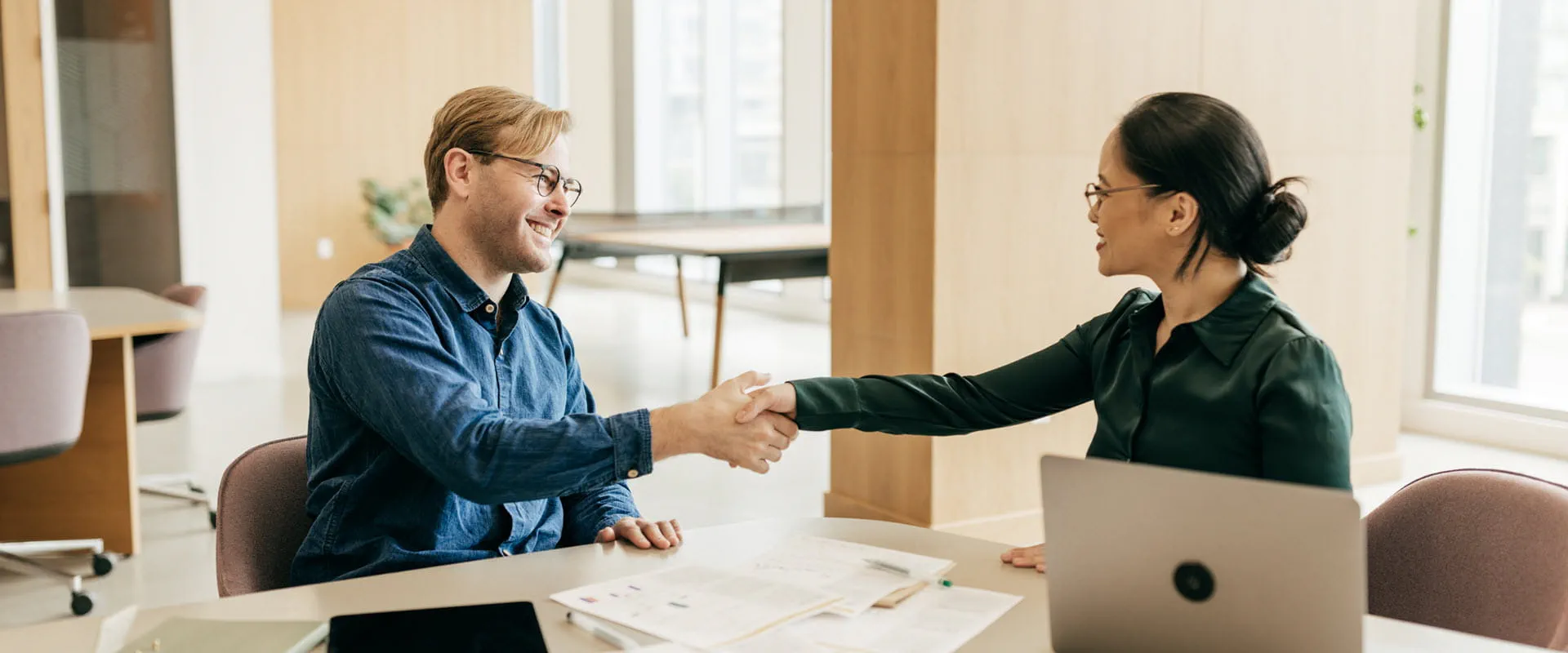 Two people having an agreeable handshake in the office during business meeting.