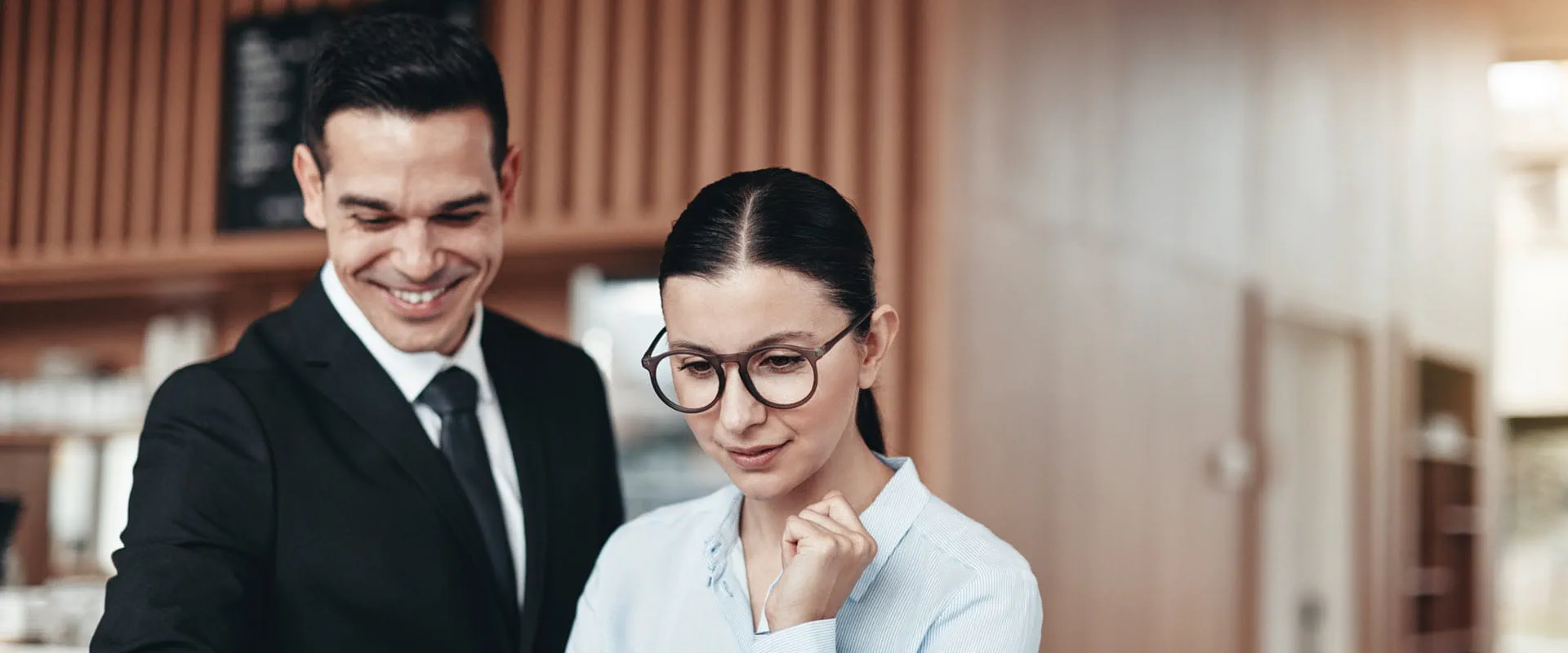 An administrative assistant and their boss look at a laptop screen