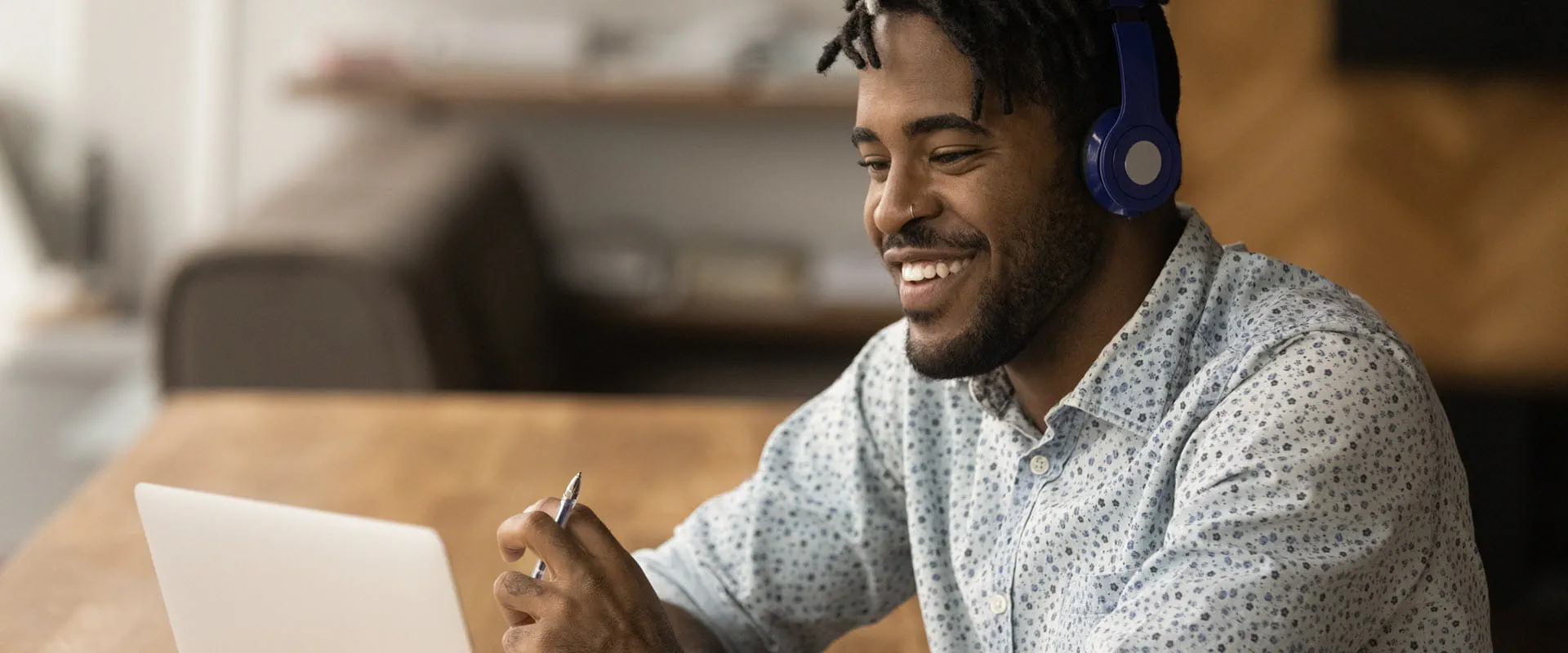 Close up smiling person wearing headphones using laptop, looking at screen.