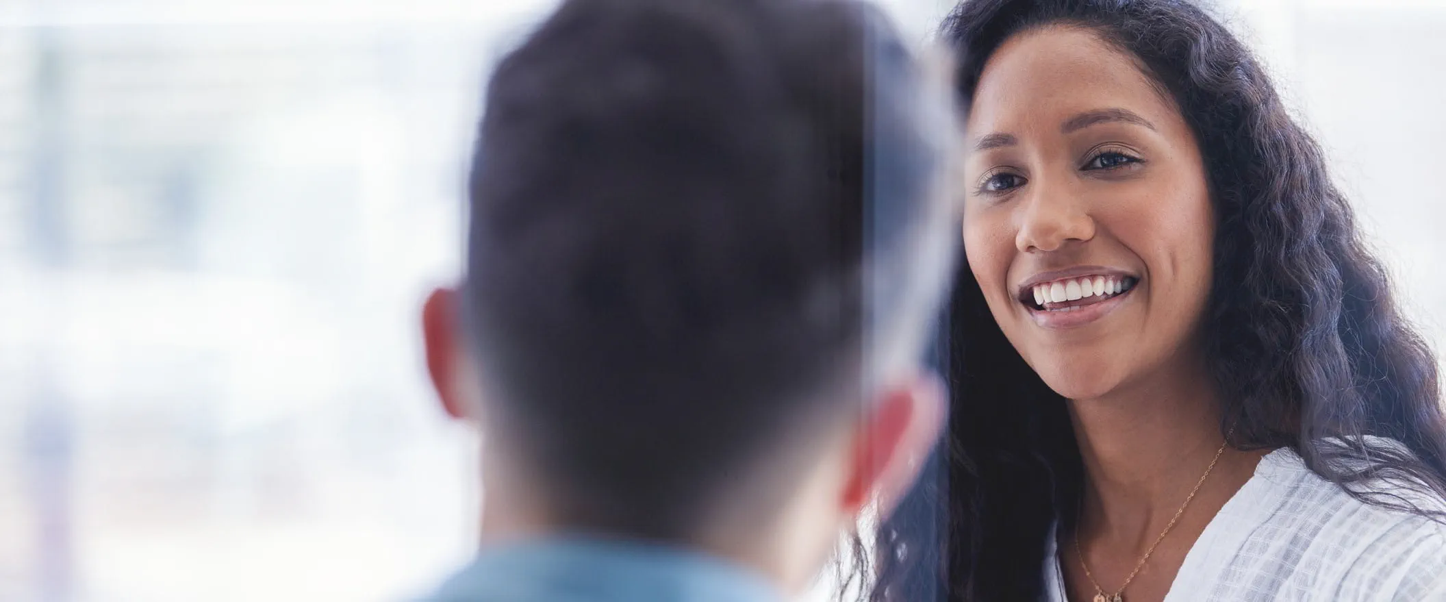 Two people talk in a glass conference room