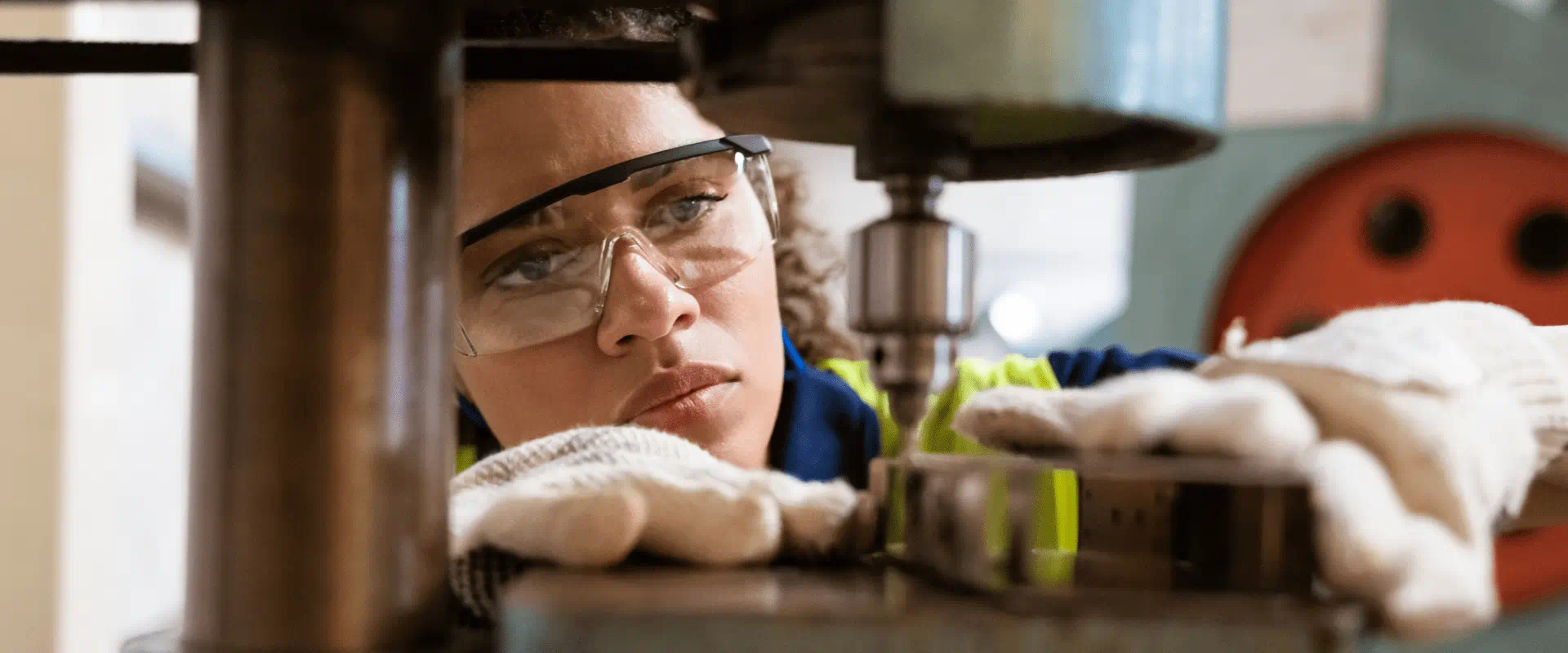 Worker in safety glasses and gloves uses a machine.