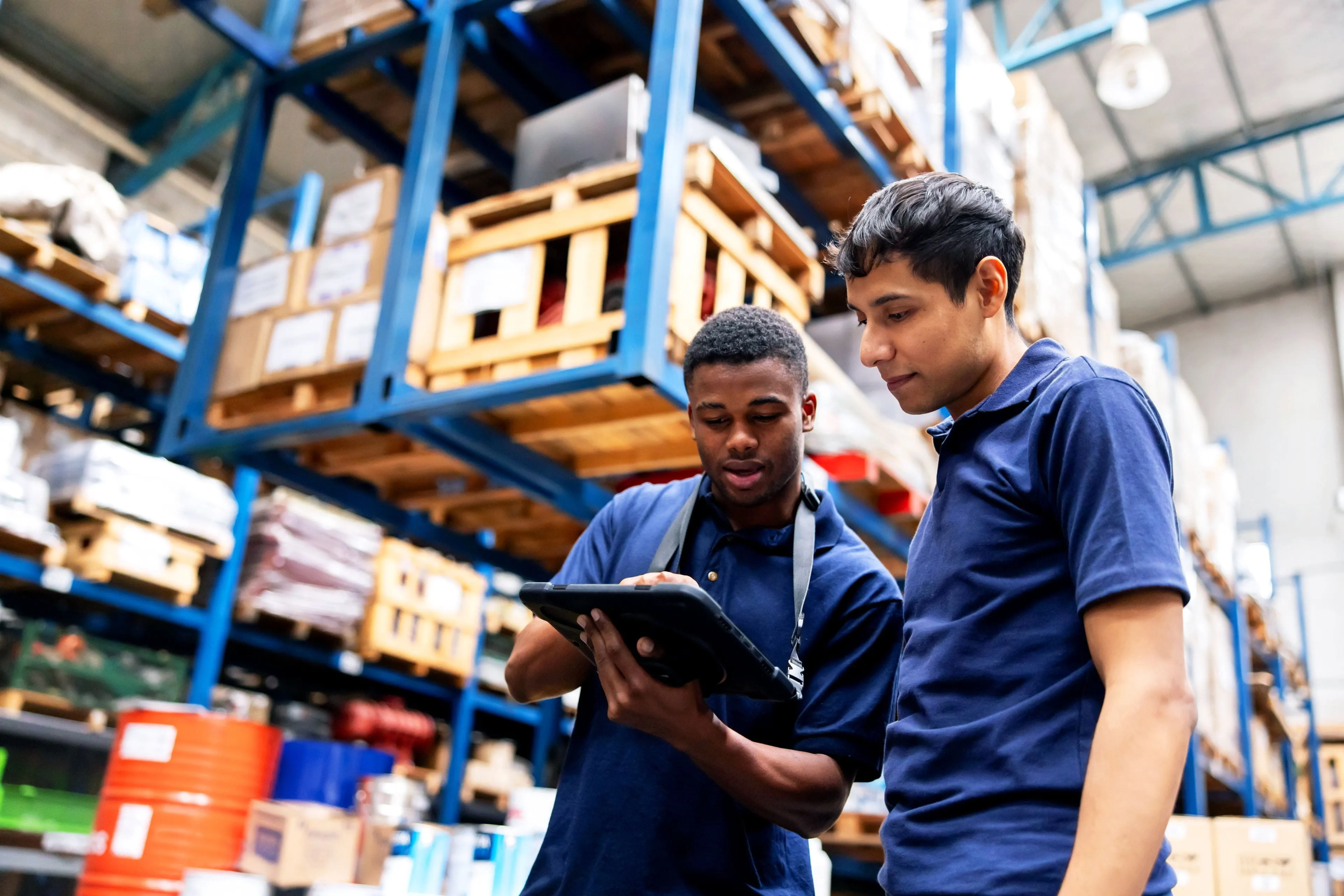 Two warehouse workers review inventory on a tablet in a distribution center