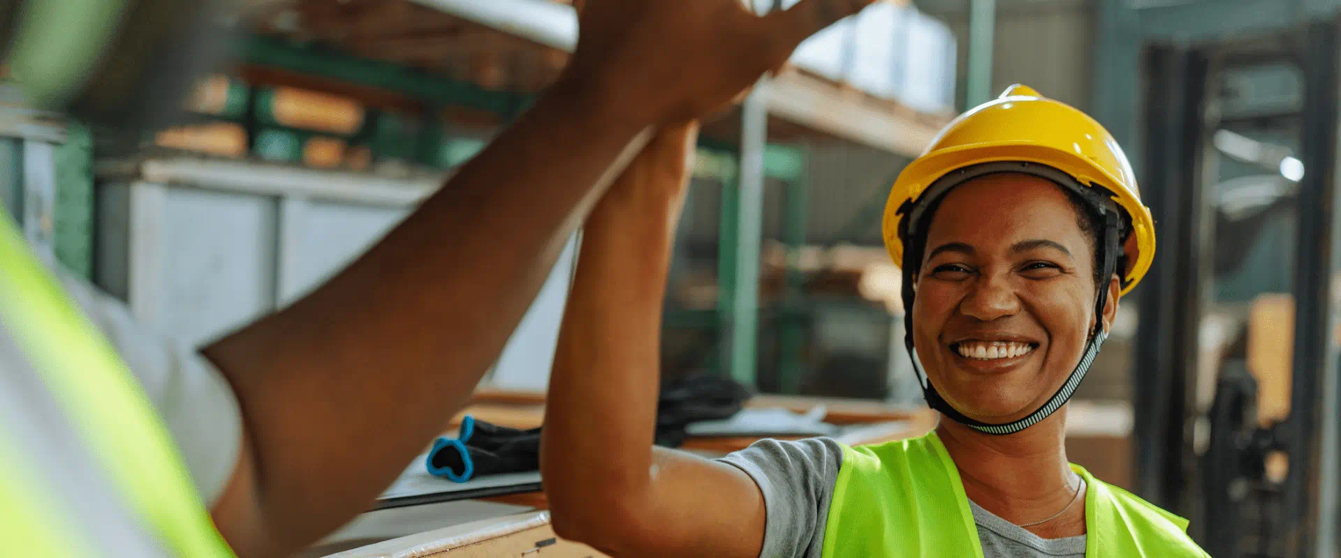 Two warehouse workers high-five.