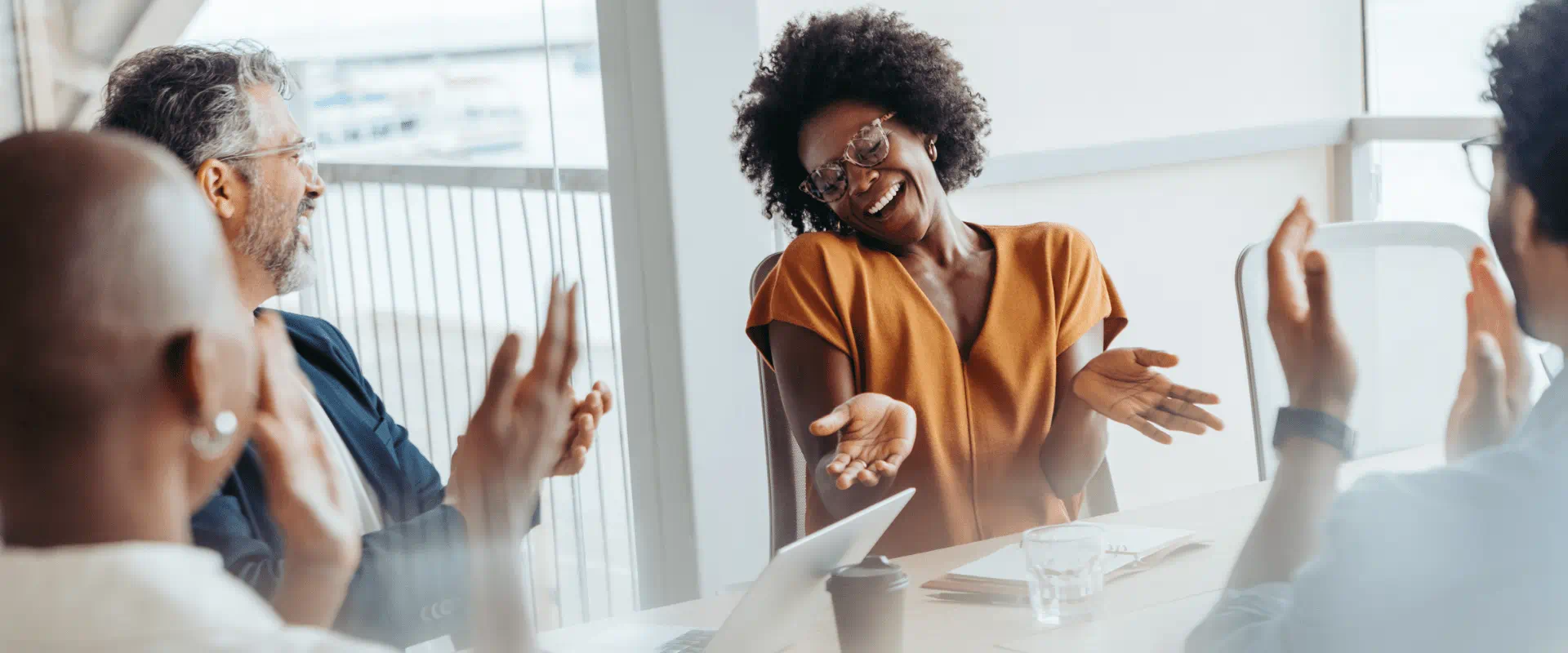 A group of people in a conference room, applauding their coworker