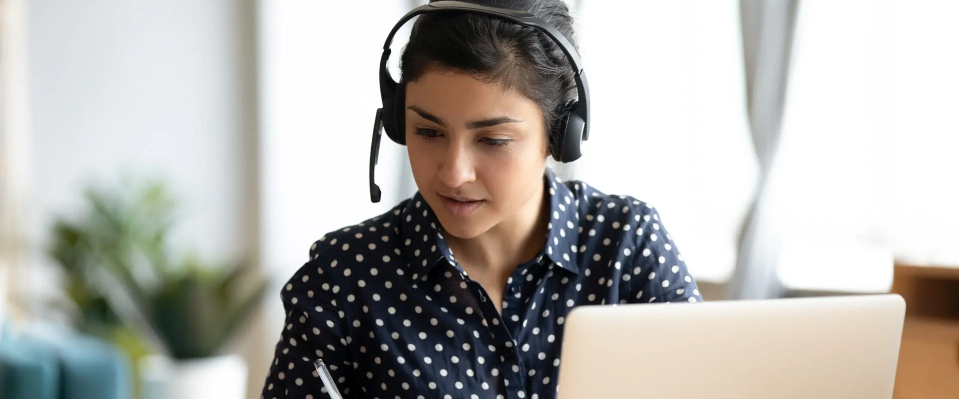 Remote worker wearing headset, taking notes.
