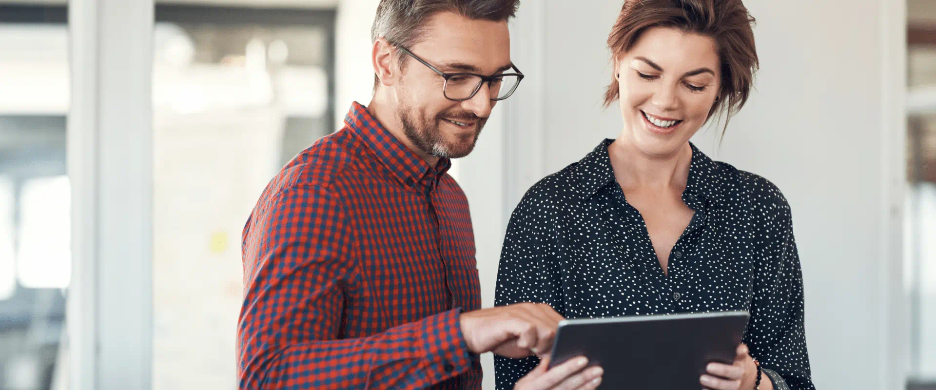 Two people stand next to each other looking at a tablet