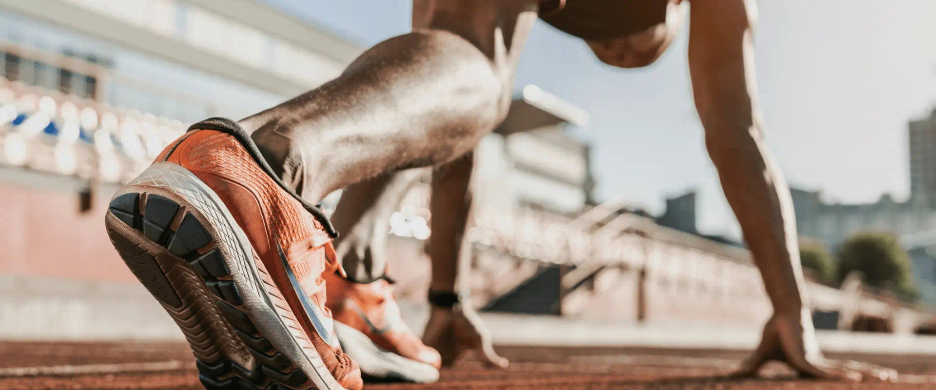 A track runner looks like they're about to start a practice run in an empty stadium.