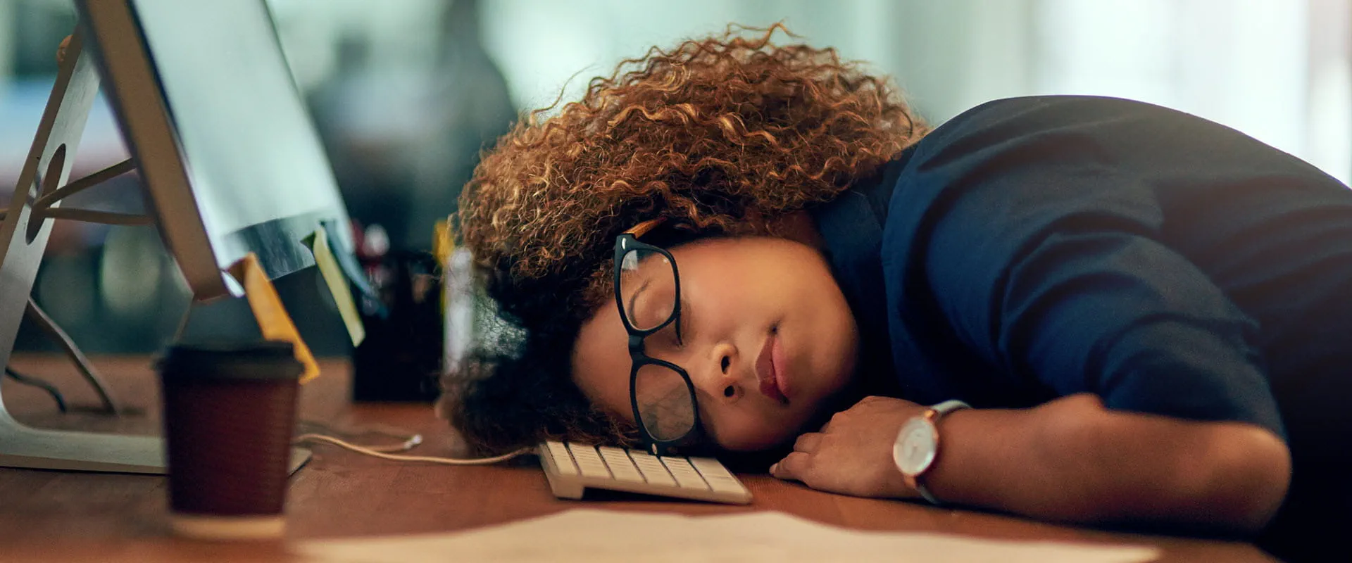 Exhausted young businesswoman sleeping at her desk.