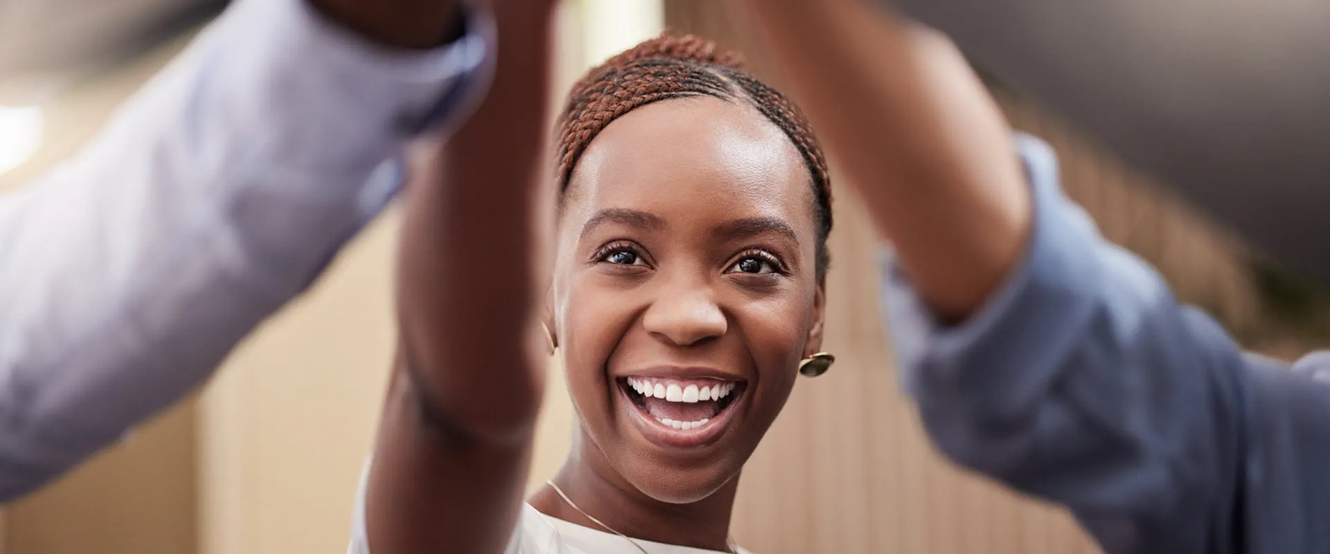A young worker smiles as they high-five other workers out of frame