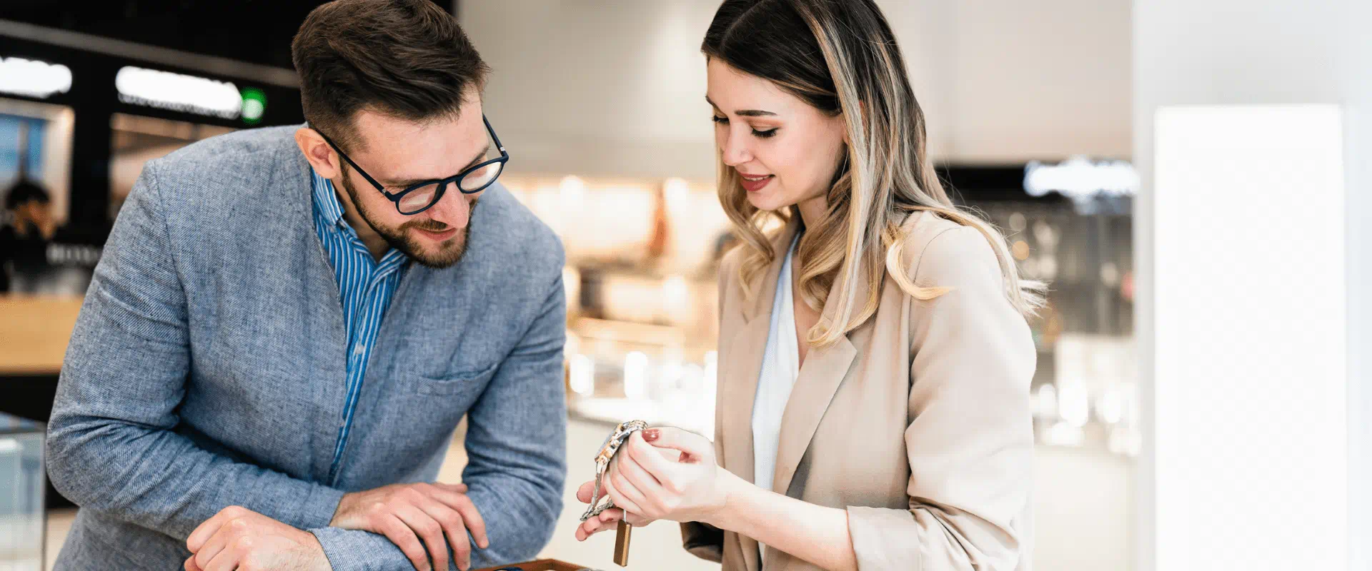 A shopper and retail worker look at a watch in a jewelry store.