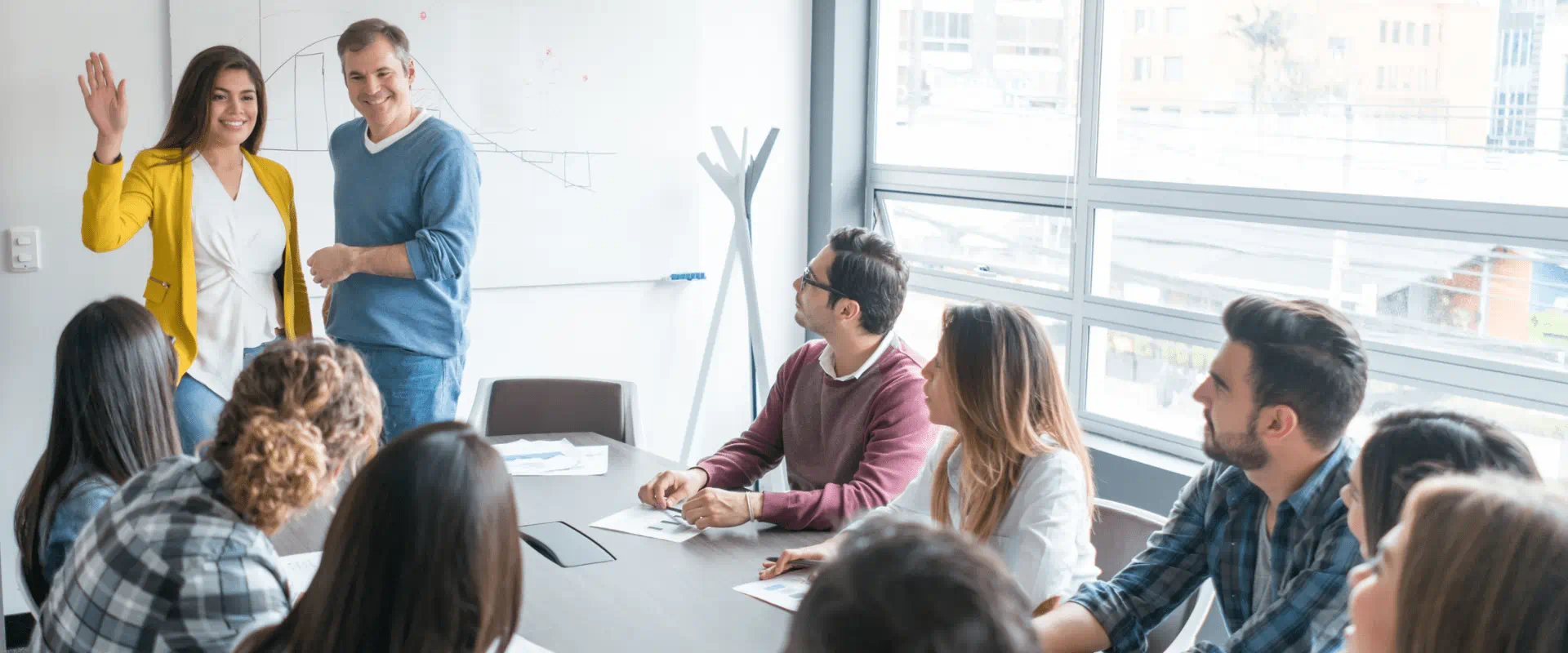 A manager introduces a new worker to a full conference room