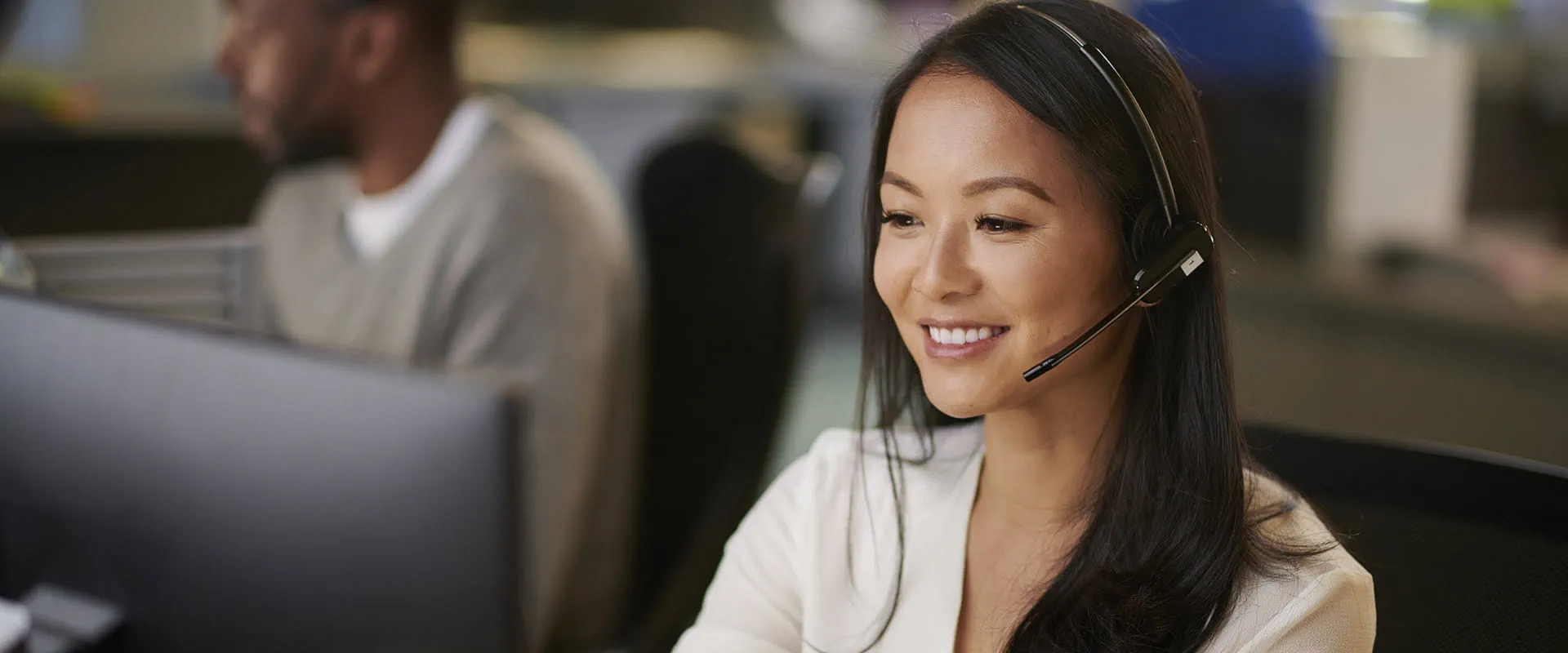 Smiling person wearing headset looking at laptop screen.
