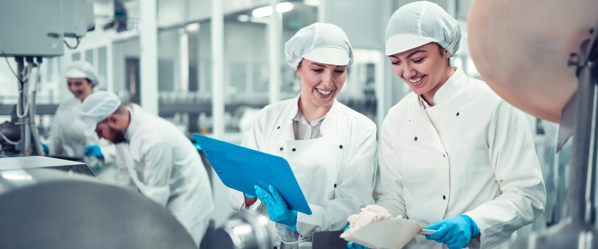 Two workers filling machine in a food manufacturing plant.