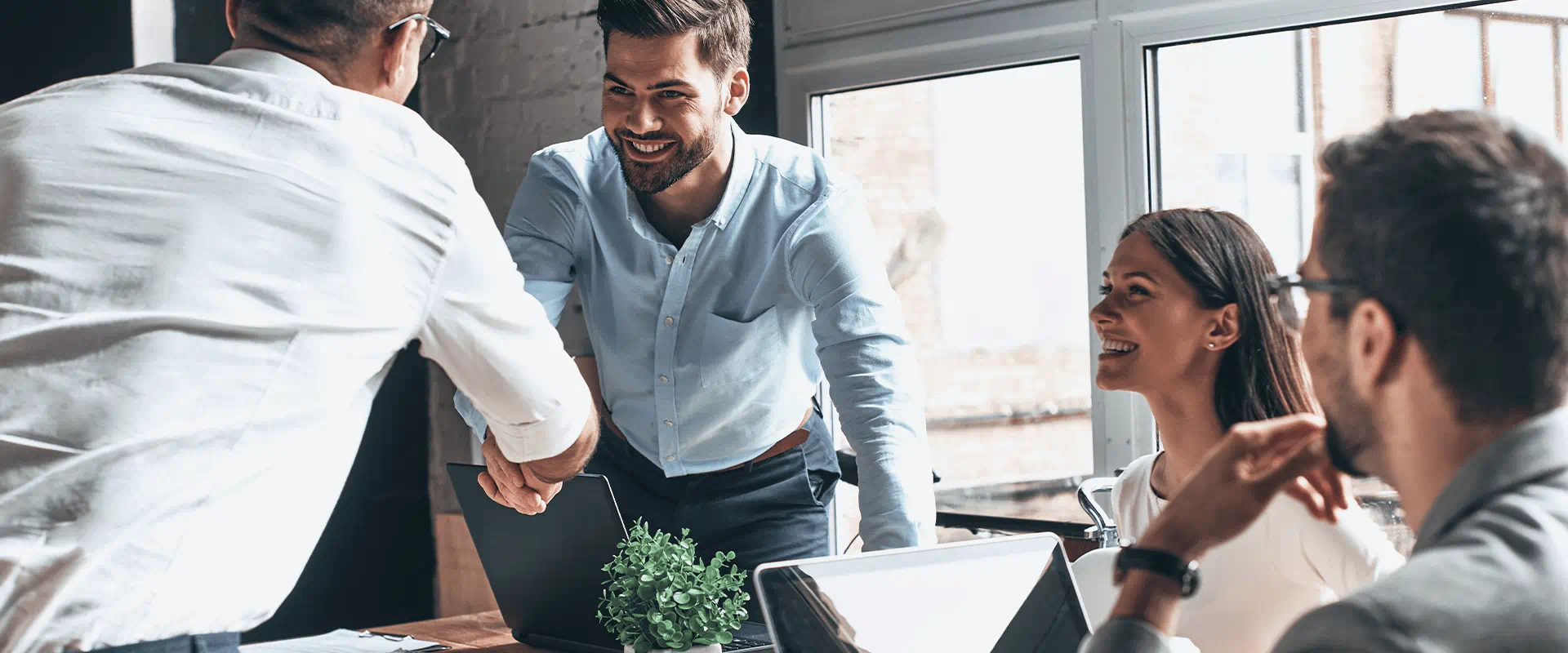 Business professionals in a modern office setting, engaging in a handshake and discussion.