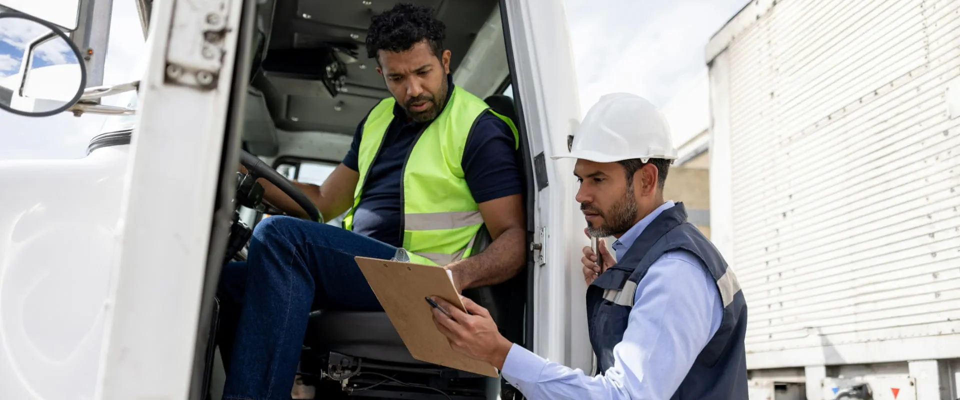 Foreperson talking to a truck driver while working at a distribution warehouse transporting merchandise