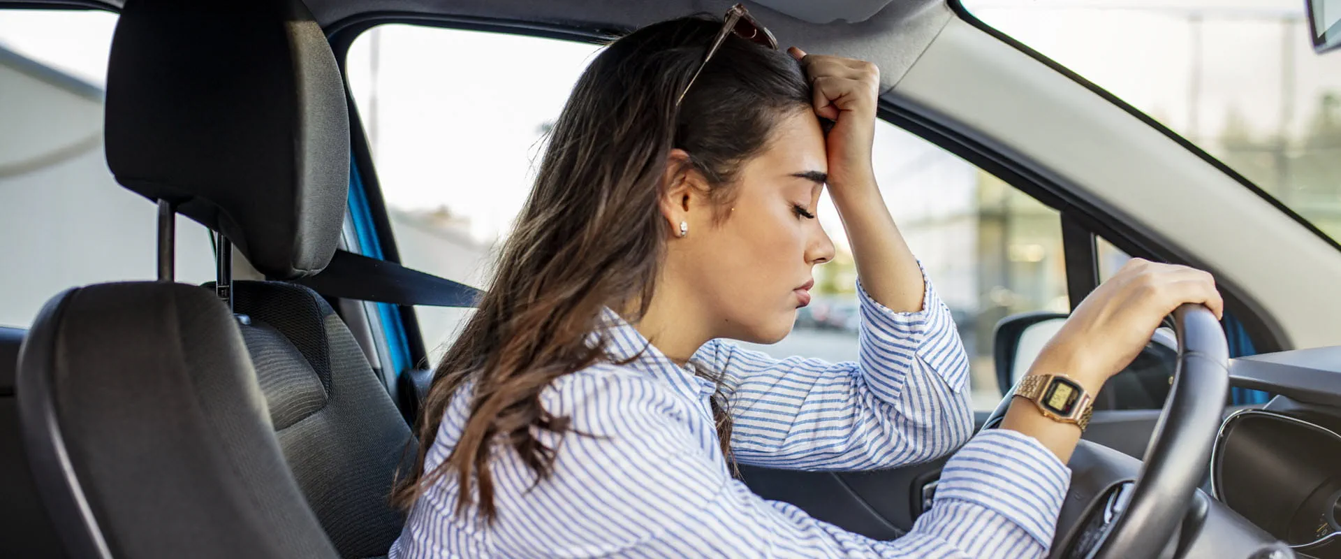 A worker sits in their car, stressed
