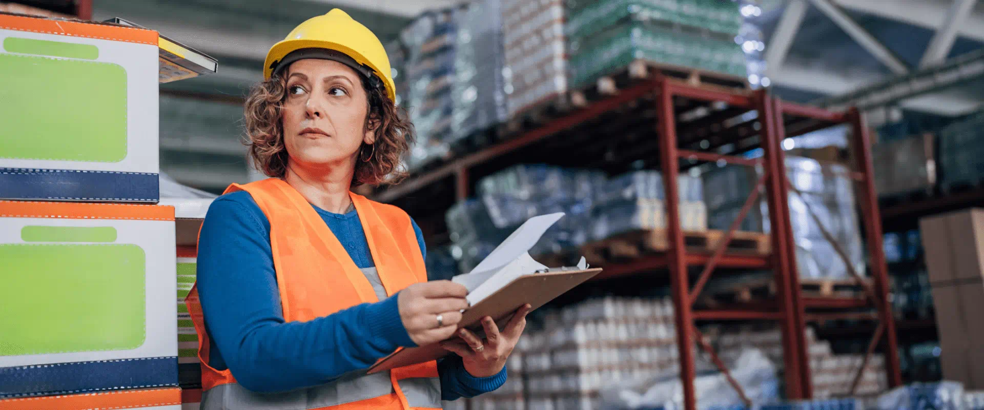A manager in a warehouse holds a clipboard