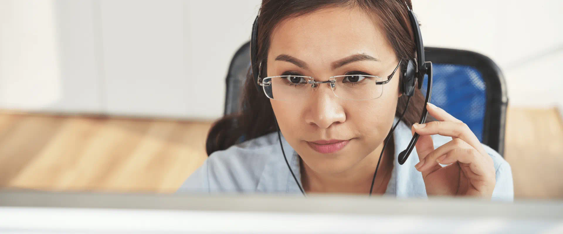 A remote worker wearing a headset looks at their computer monitor while on a call.
