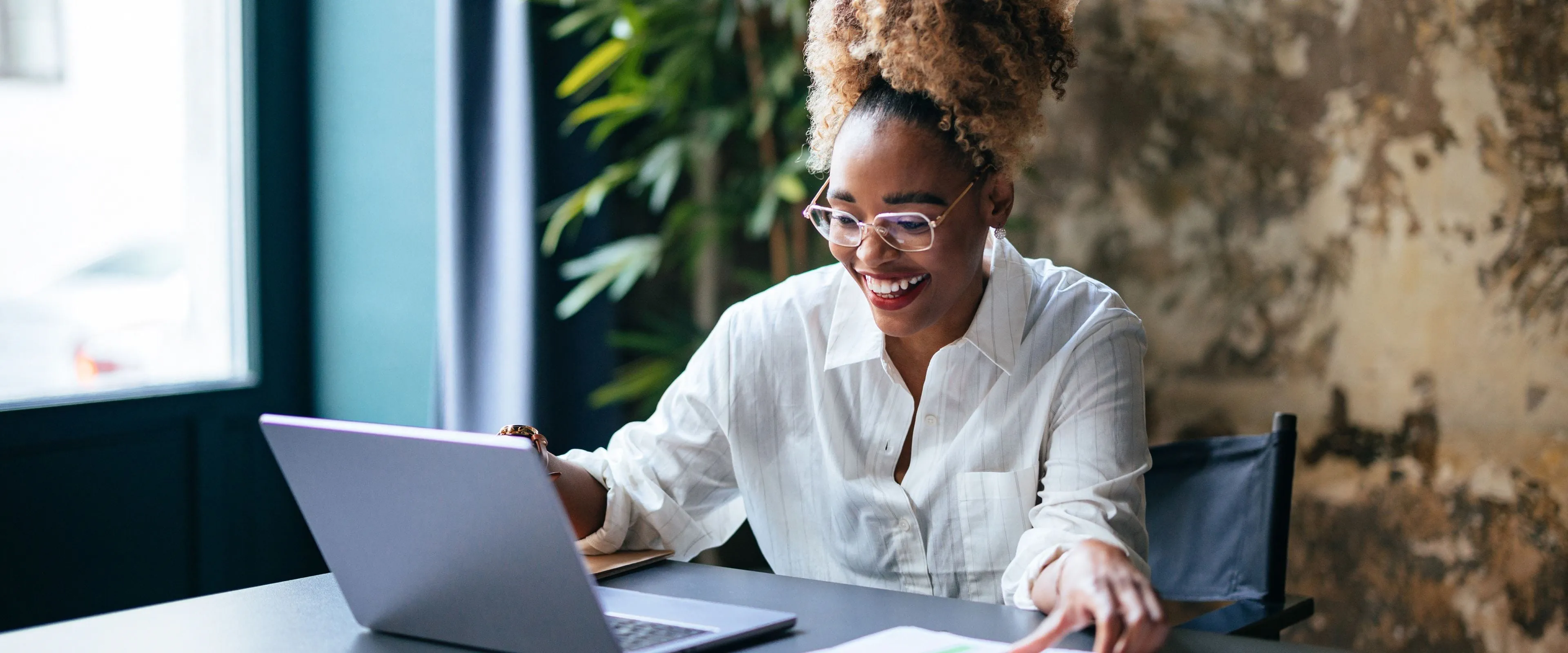 A professional worker sits at a laptop computer, smiling