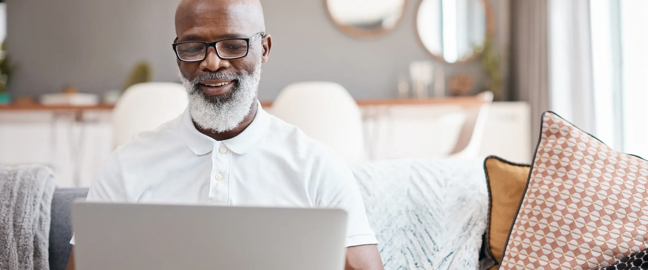 A person sits at home on a sofa, looking at their laptop