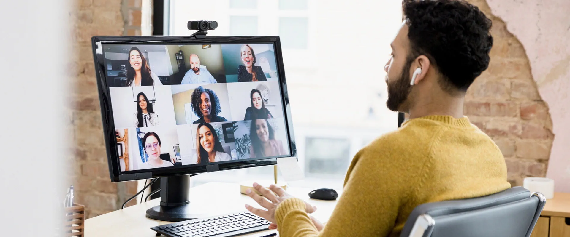 Person sitting at a desk in an office meets virtually with team members.