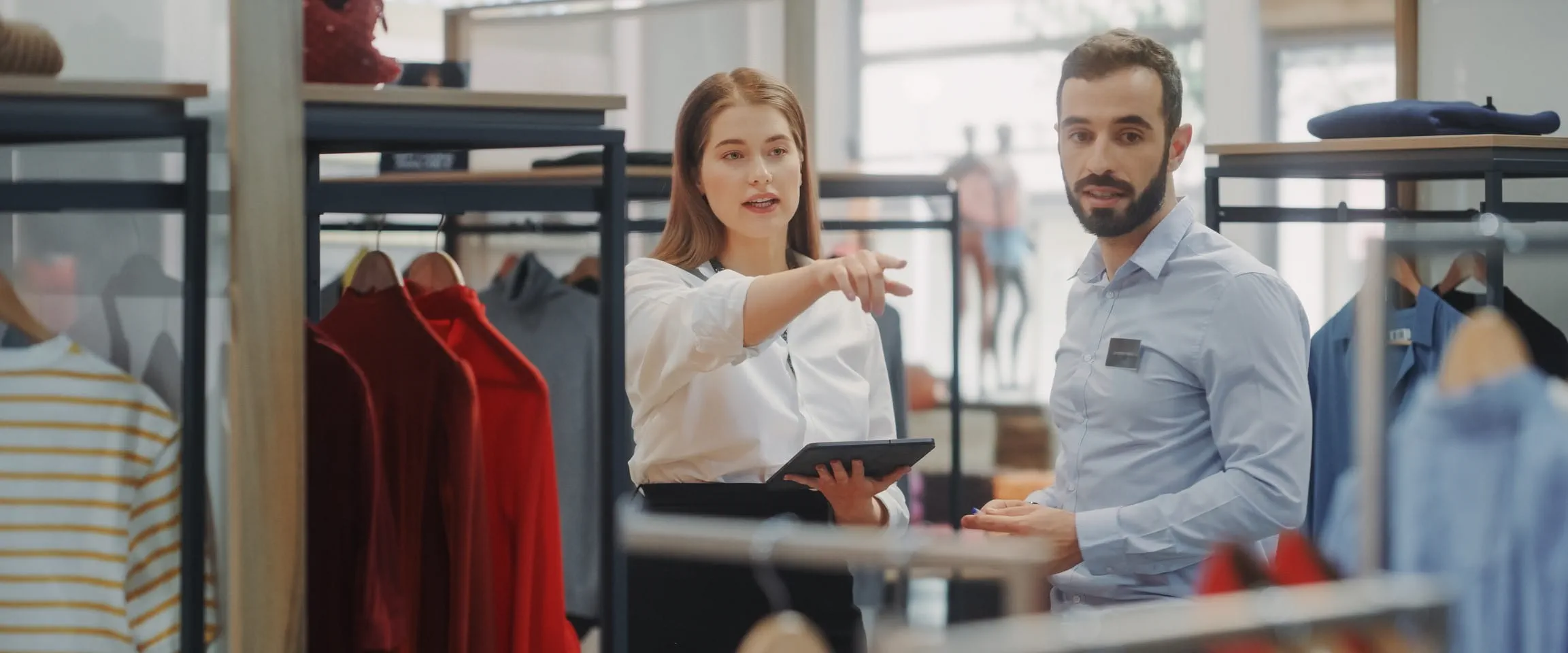 Two retail employees in a clothing store are talking together.