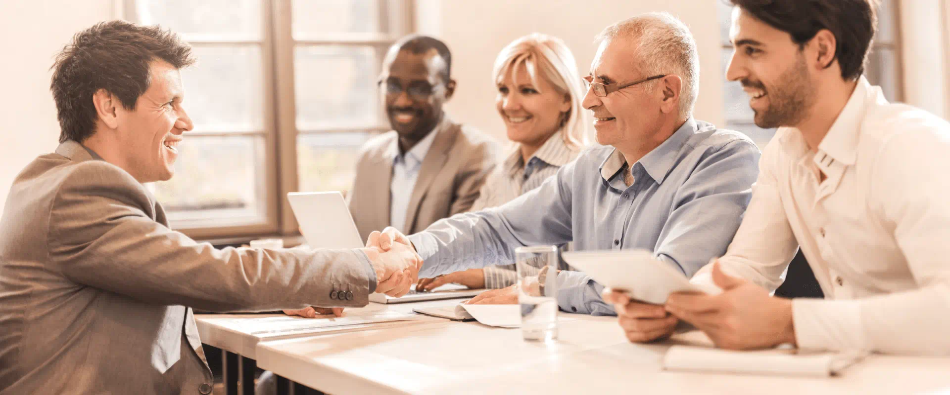 Business professionals in a meeting room exchanging a handshake.