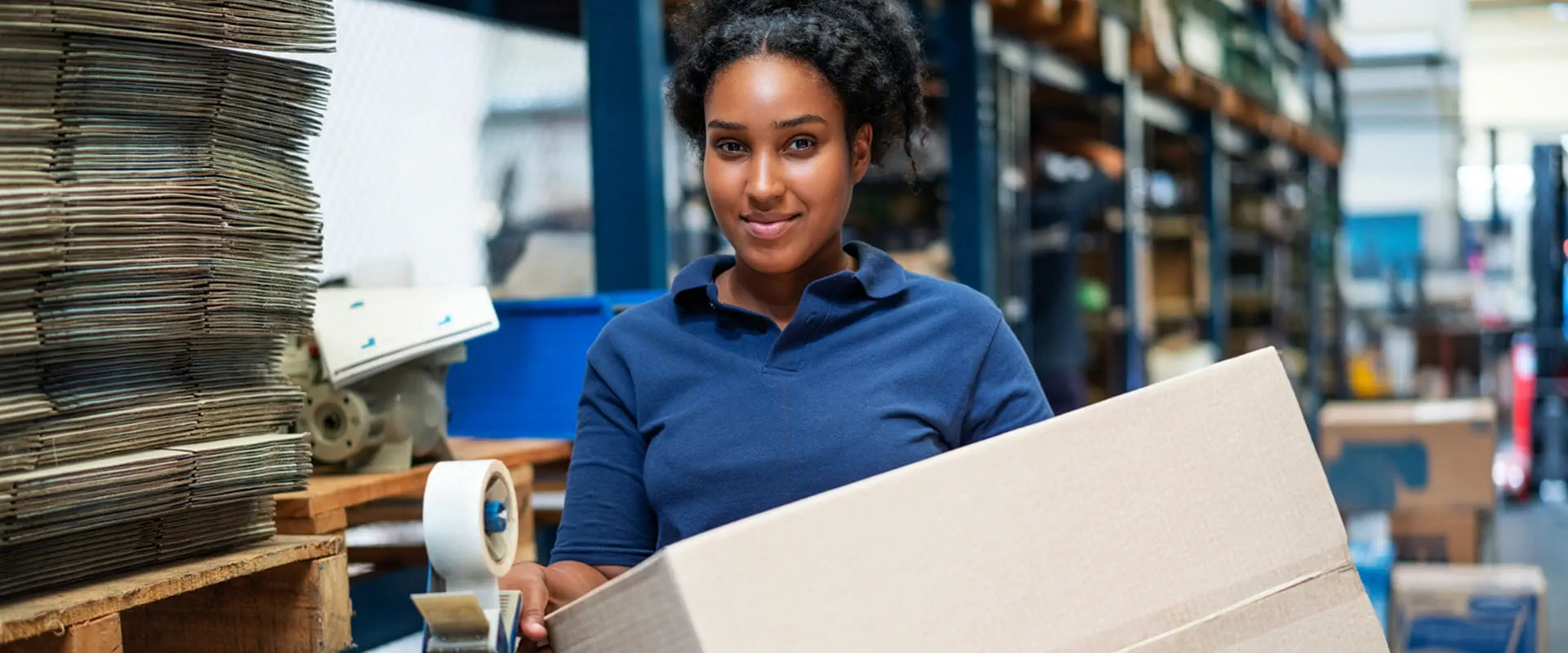 Worker moving a box in distribution warehouse. 