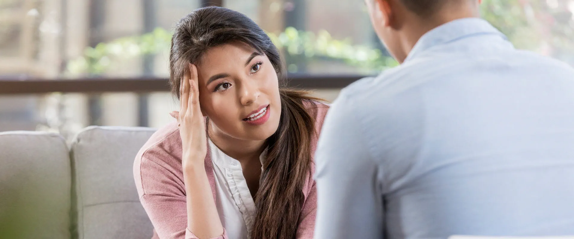 A concerned individual in a pink cardigan engaged in a thoughtful conversation with another person in a light blue shirt.