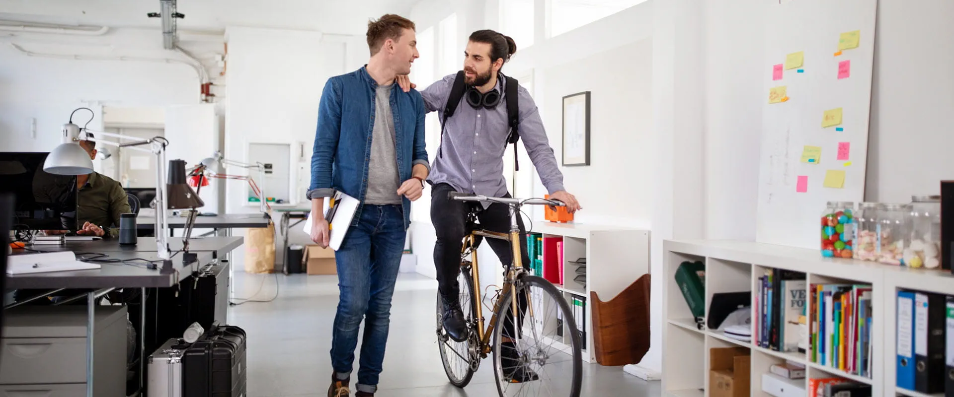 Office workers discussing work in the office, one colleague on a bicycle.