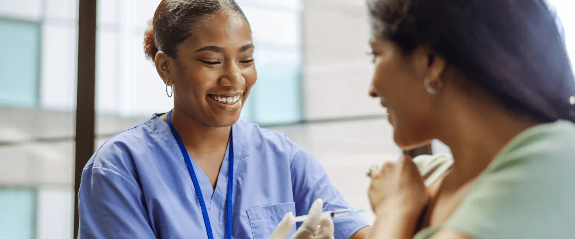 A nurse smiles at a relaxed patient while they're preparing a syringe