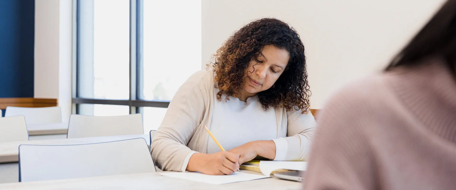 Adult woman sits at a table taking an exam.