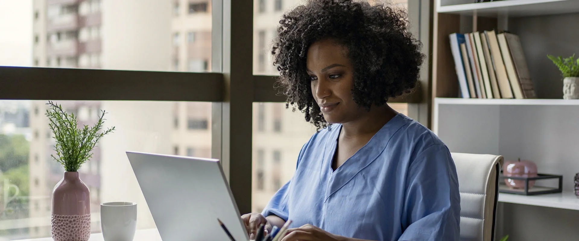Nurse sitting at a desk, working on a laptop.