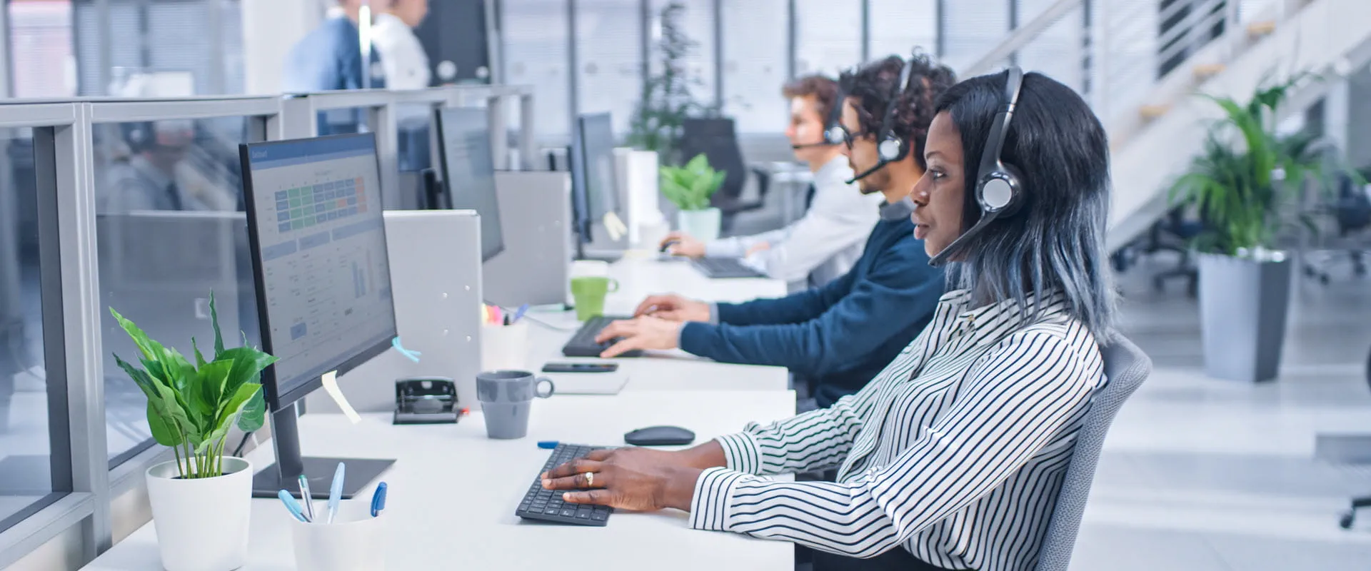 Team of customer service operators working at call center wearing headsets and actively taking calls.