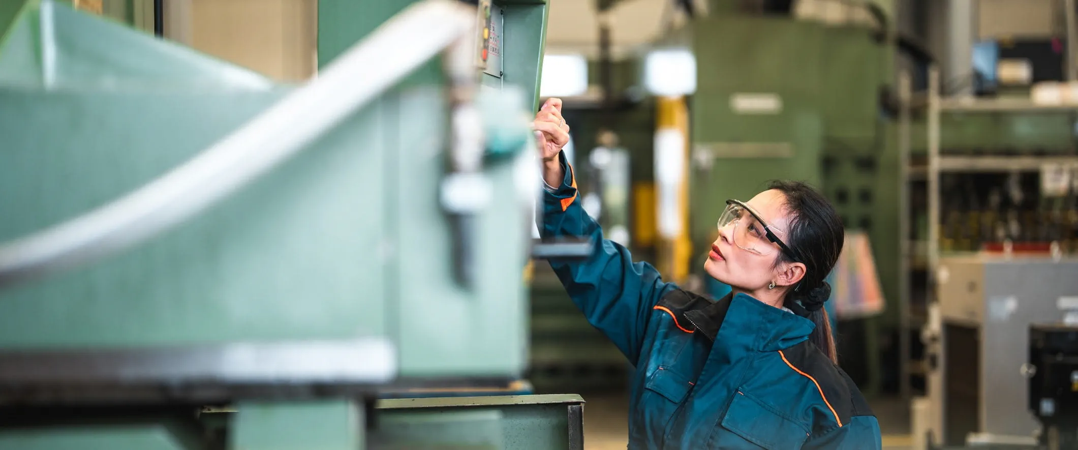 A worker in safety glasses inspects a large piece of equipment.