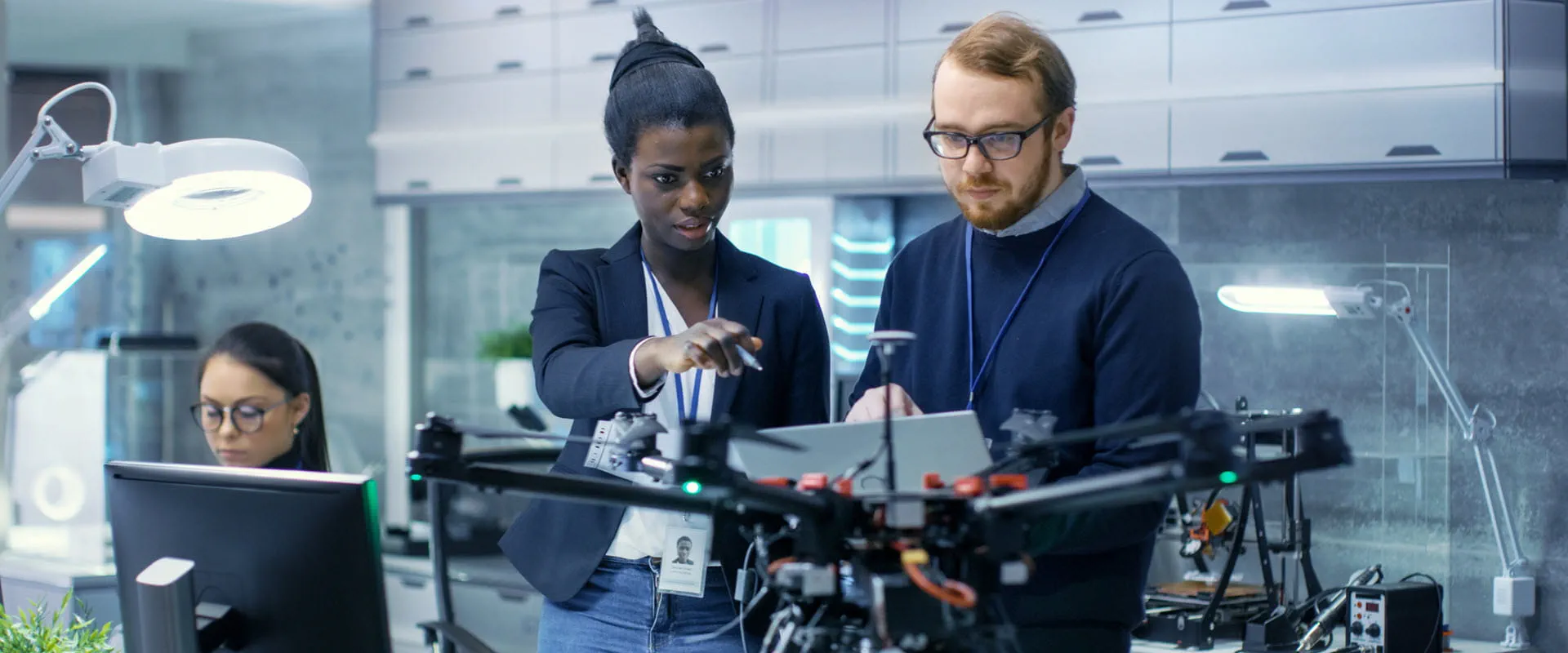 Two engineers working on a drone project with help of laptop and taking notes
