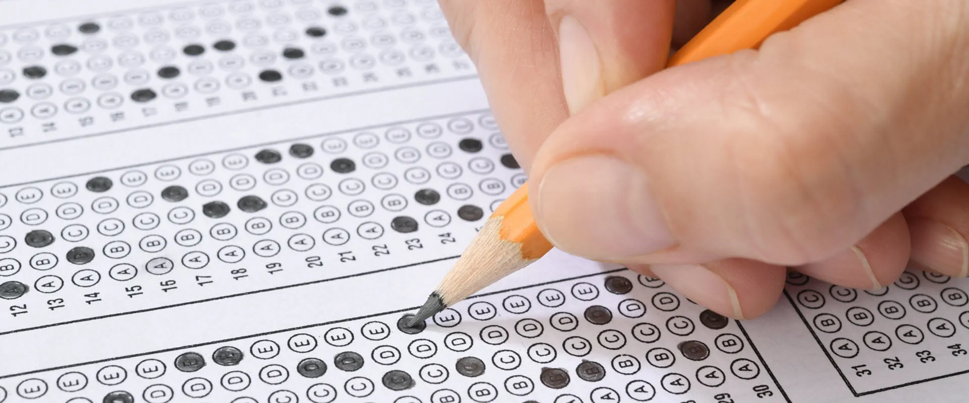 Student filling out answers to a test with orange pencil